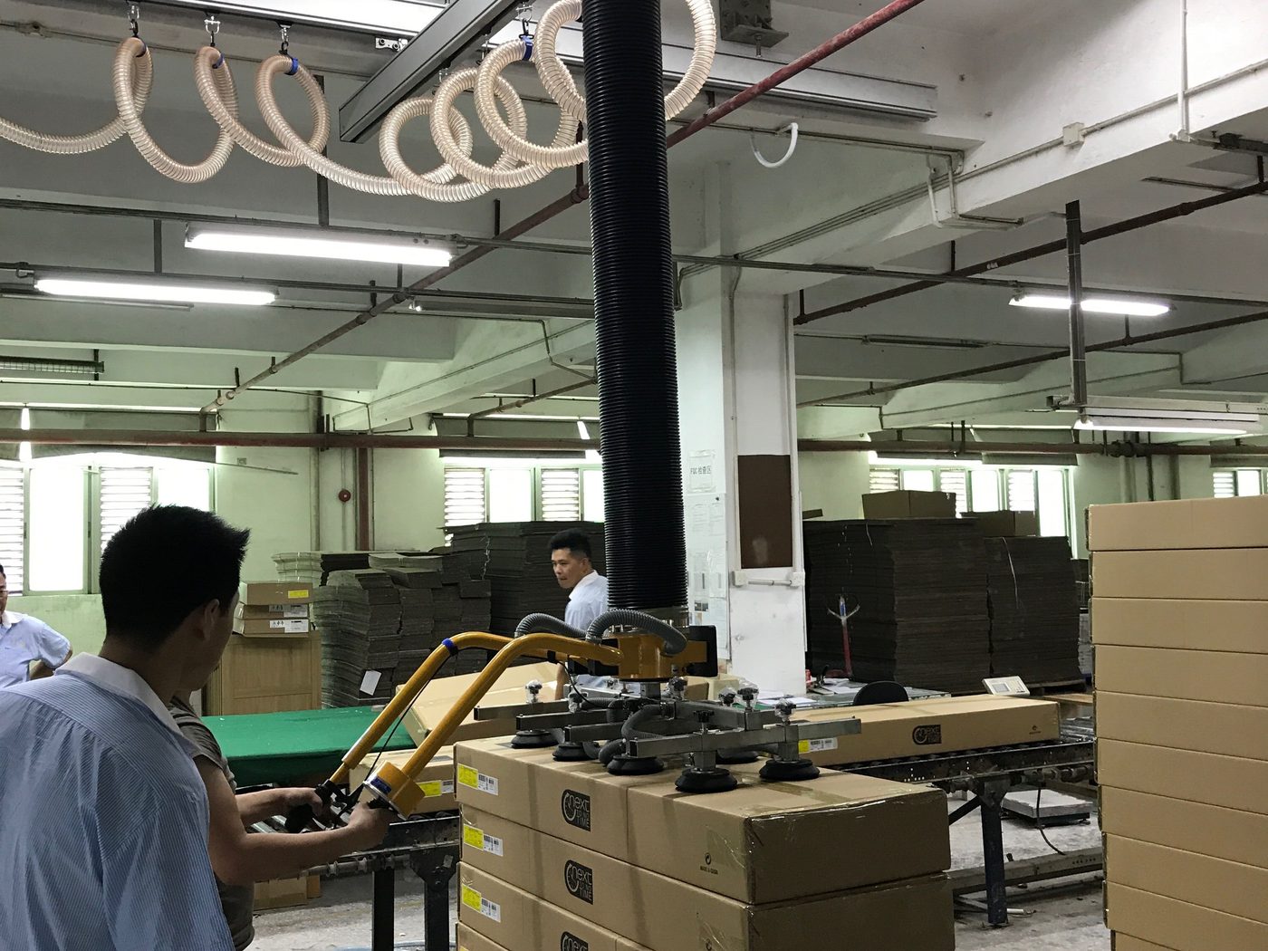 Two-handle ESL-MD vacuum tube lifter stacking cartons on a pallet